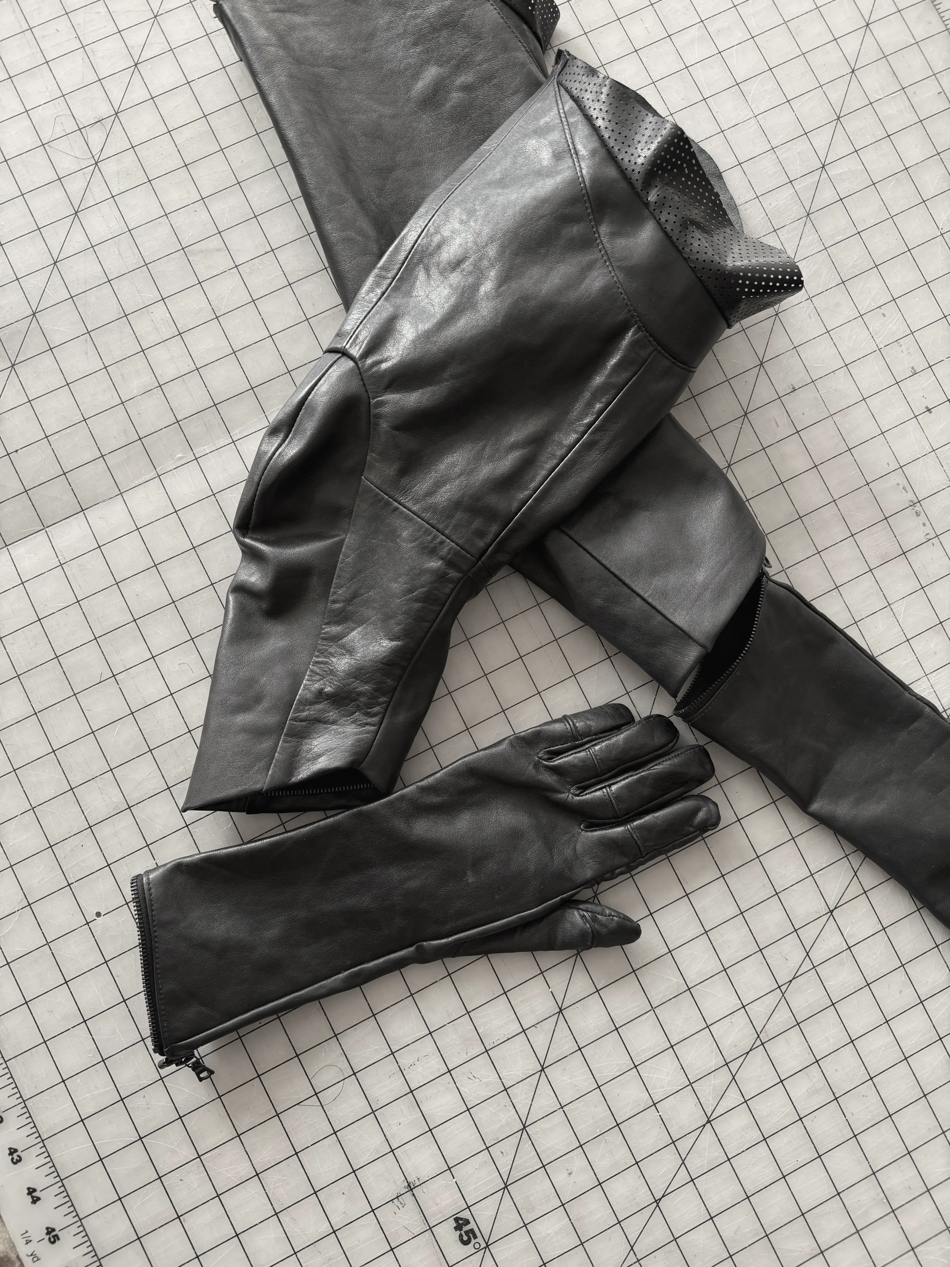 Close view of the zip that joins a black leather sleeve cuff to a long leather glove, with perforated lining turned back at the top.